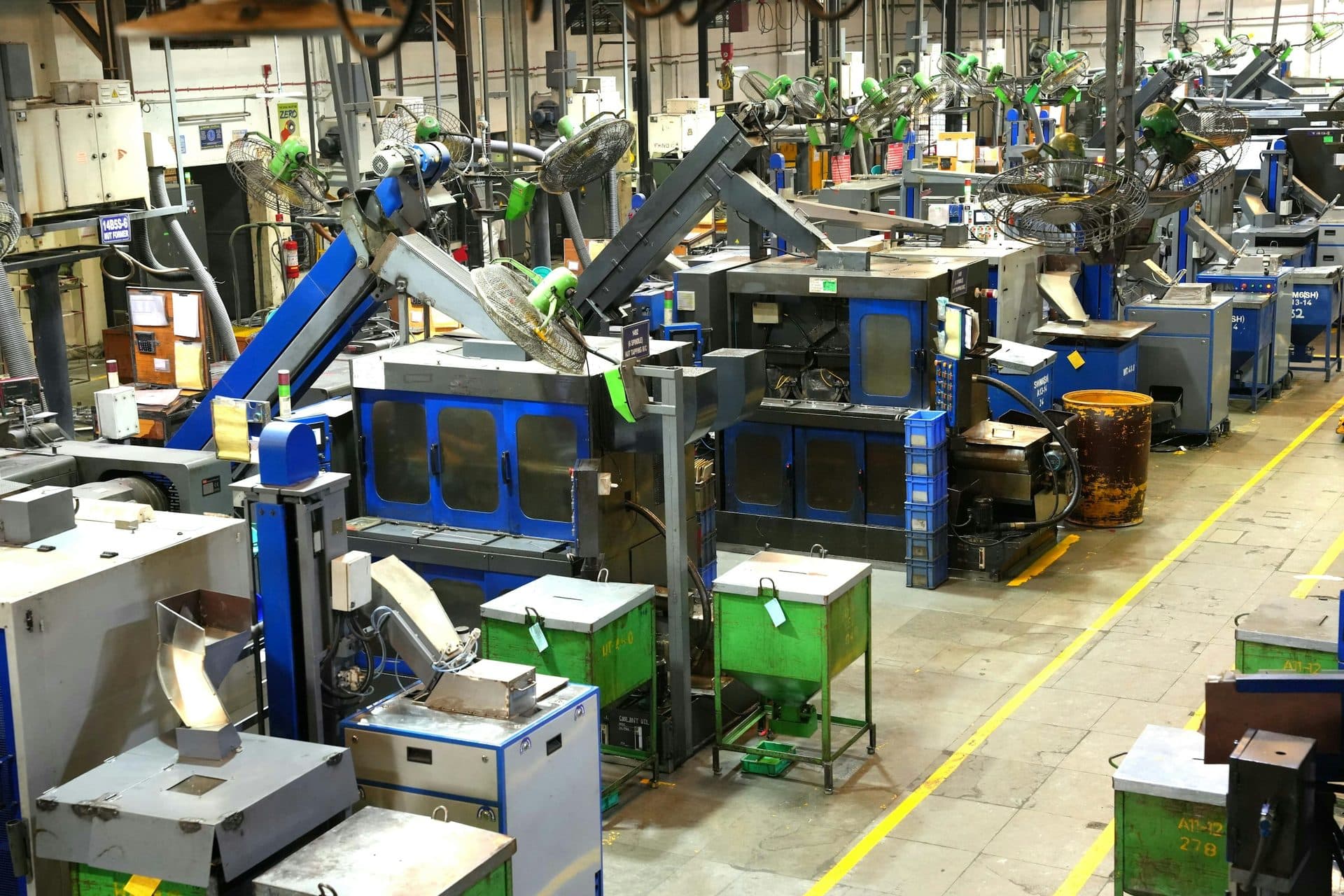 Productiehal van bovenaf met een rij machines langs gele looplijnen