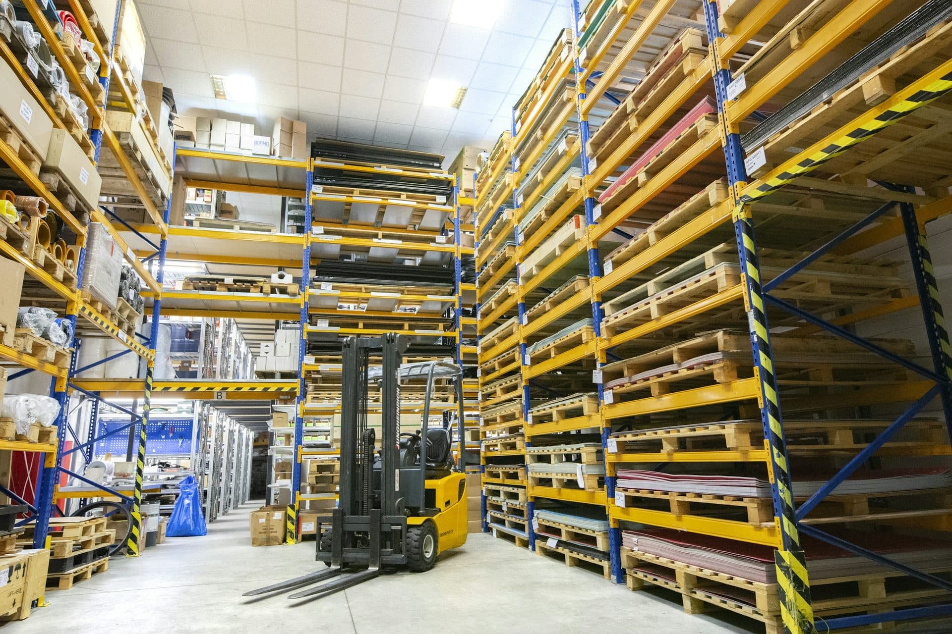 Heftruck tussen hoge palletstellingen in een magazijn