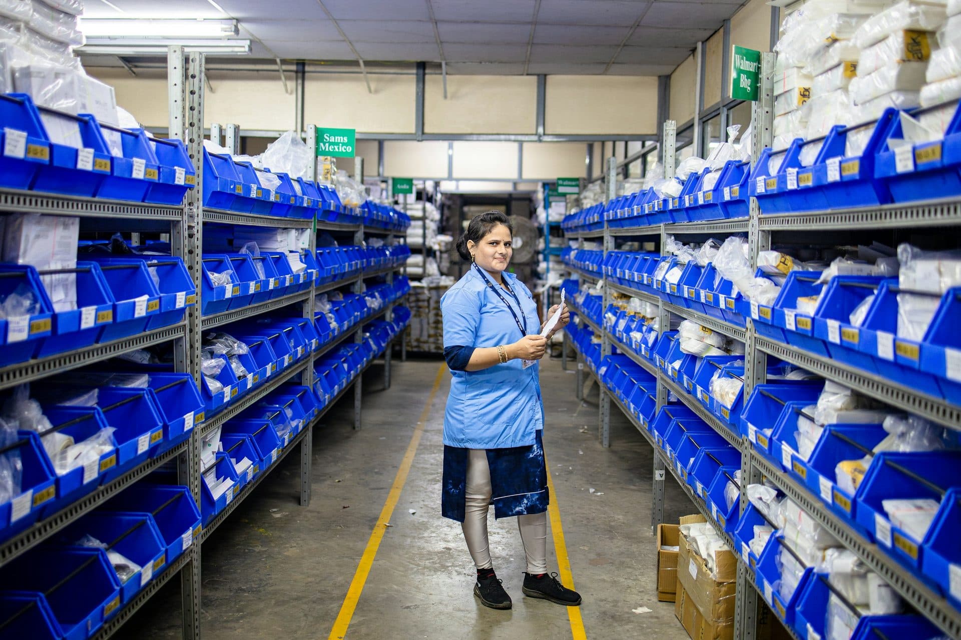 Orderpicker in een gangpad vol blauwe opslagbakken