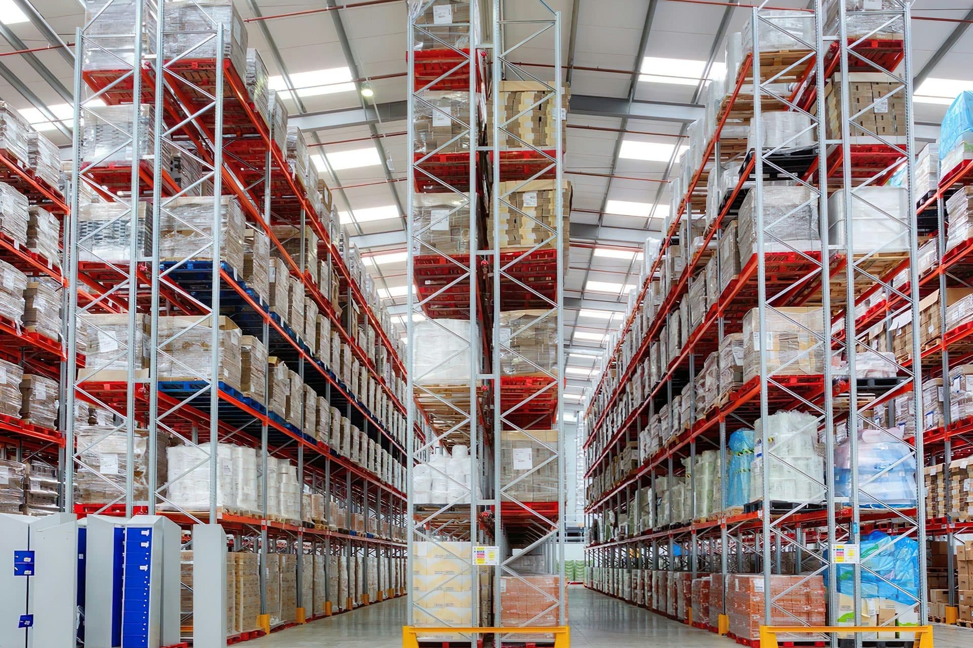 Volle palletstellingen aan weerszijden van een lang magazijngangpad