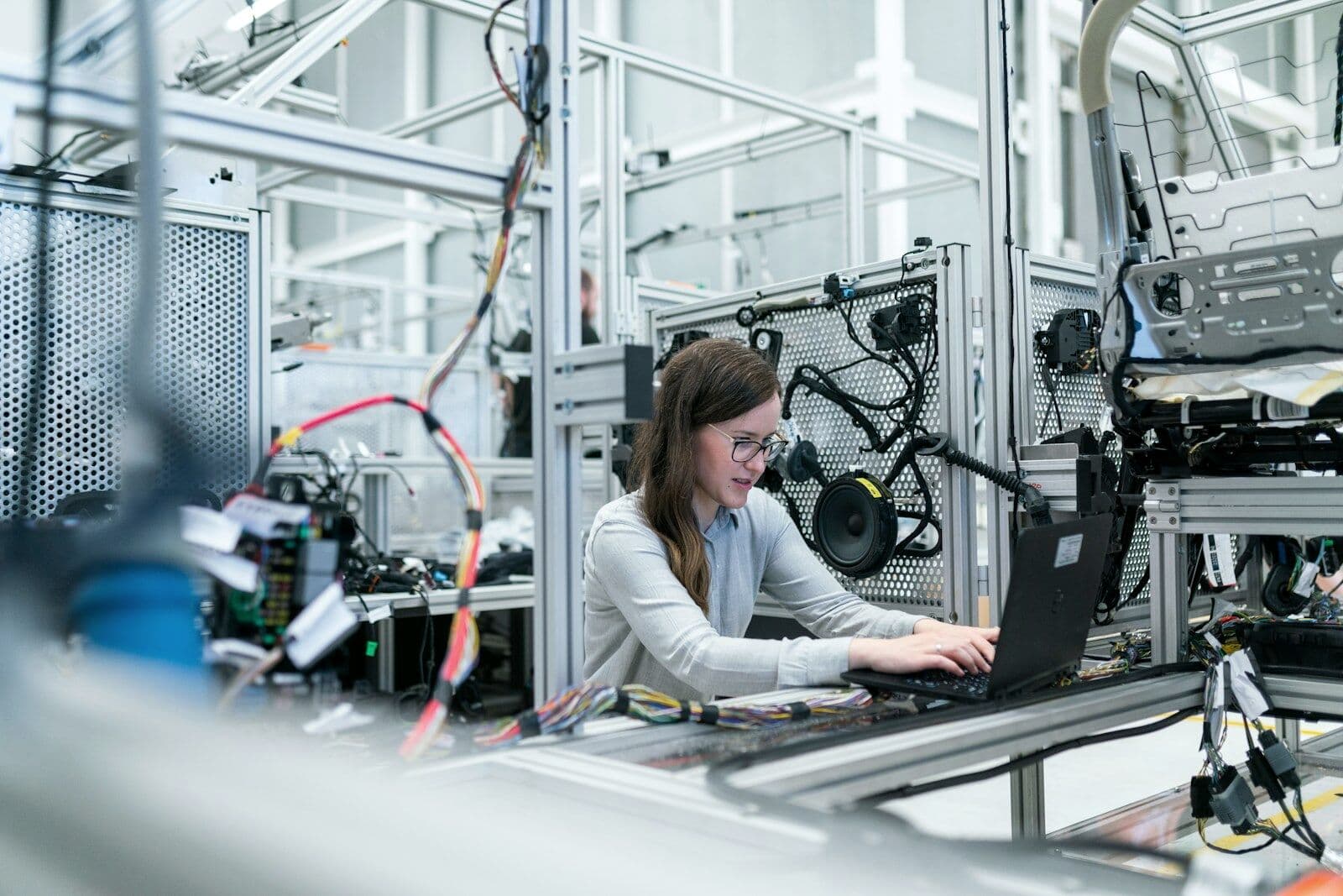 Engineer working on a laptop between the machines on a factory floor
